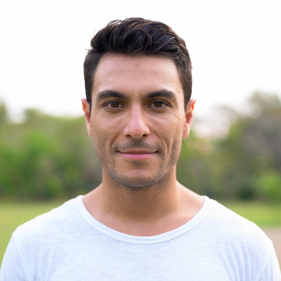 Face of young handsome Hispanic man at the park